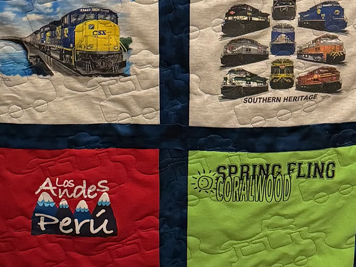 Close-up of the completed Auburn send-off t-shirt quilt showing the custom Tiger applique corner blocks and train pantograph quilting stitches across the shirt blocks, Atlanta studio