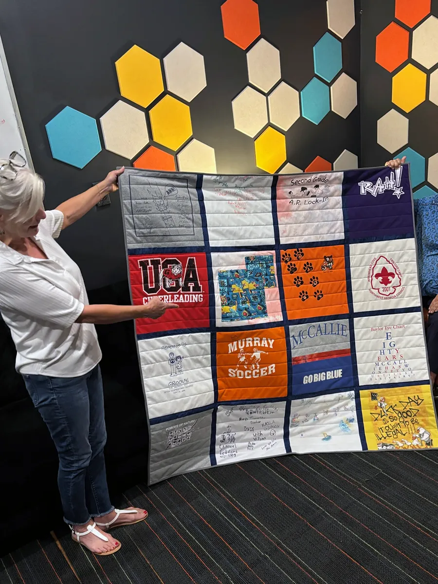 First side of the double-sided t-shirt quilt laid out flat, showing middle and high school shirts arranged in a balanced grid pattern