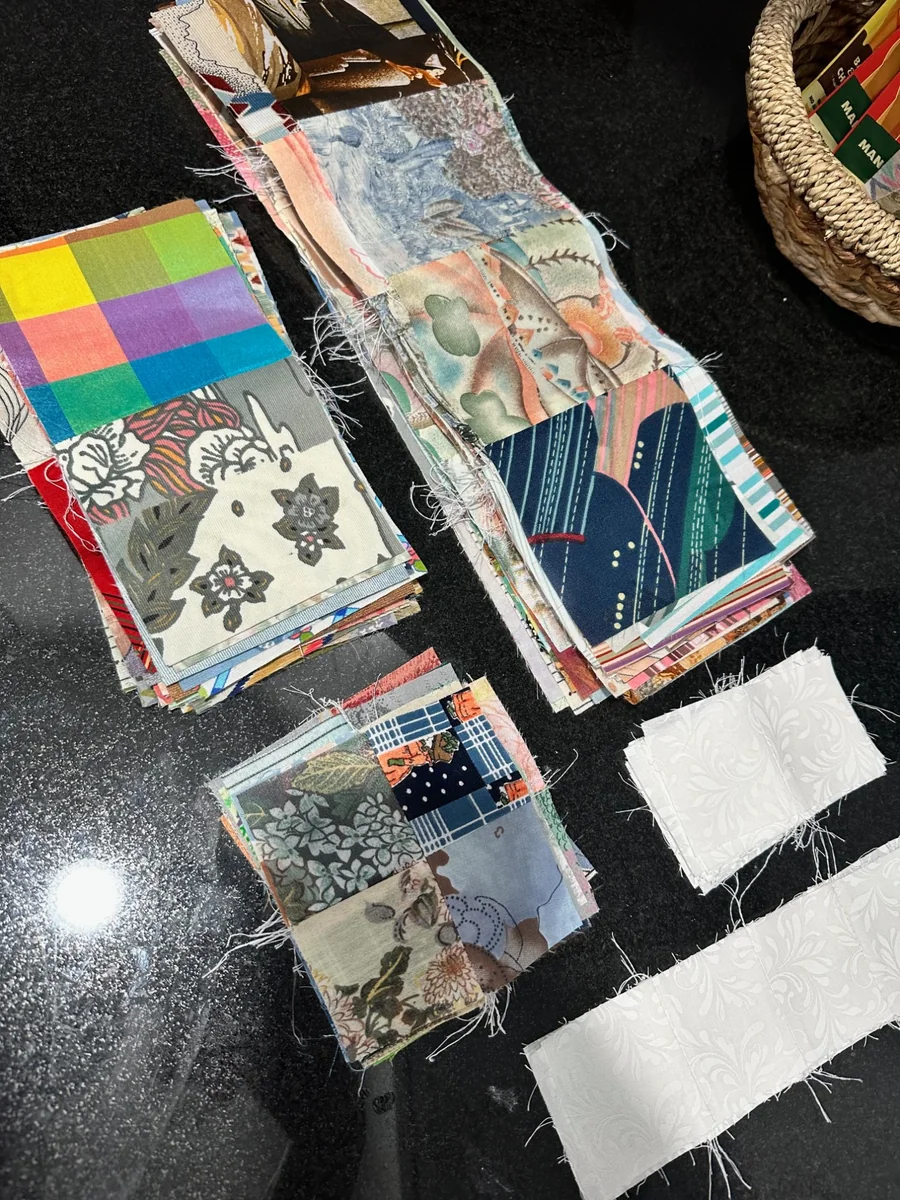 Stacks of colorful quilt fabric scraps laid out on a black work surface