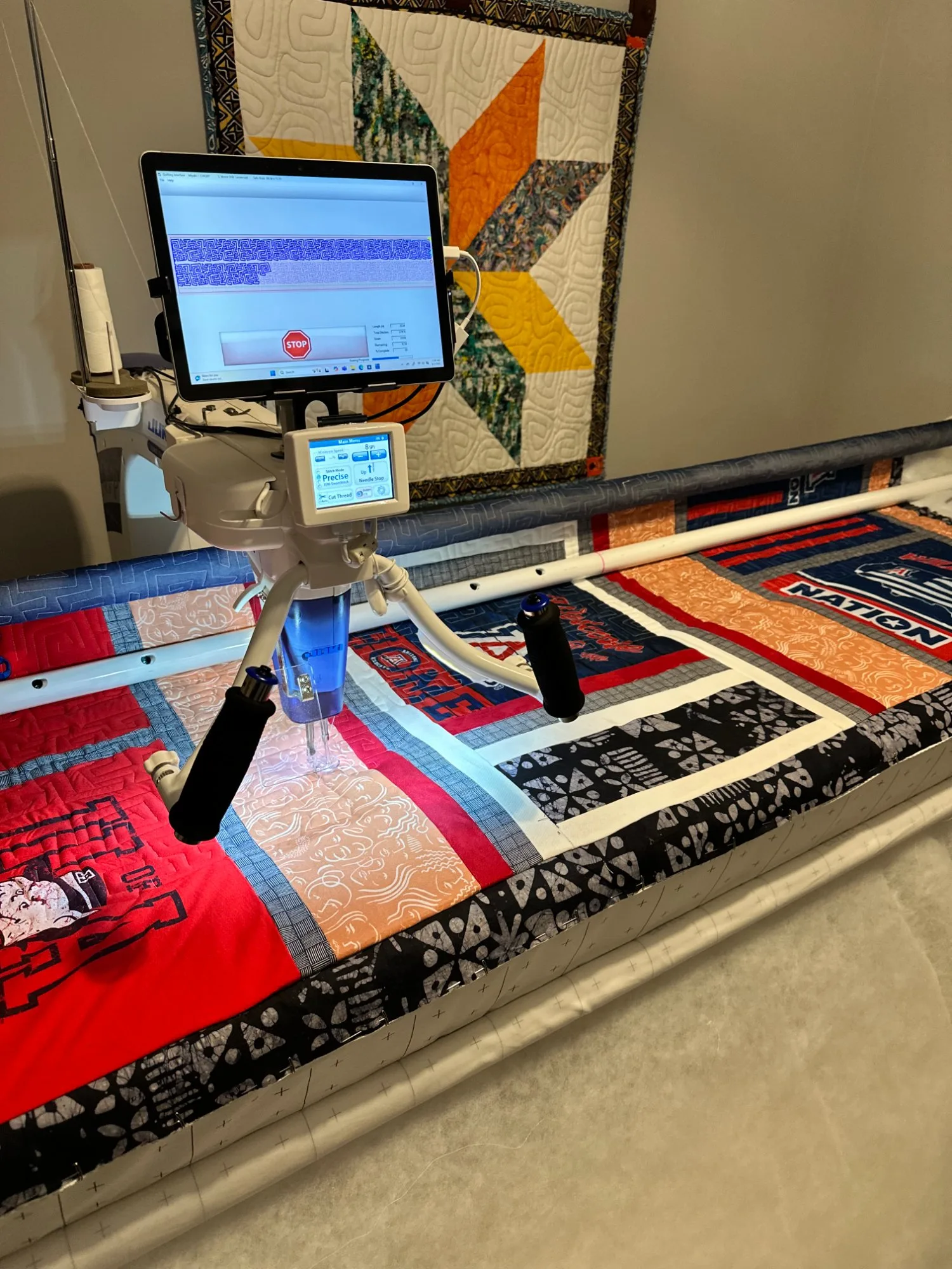 Long arm quilting machine working on a red, black, and white t-shirt quilt with custom quilting pattern stitched across the blocks