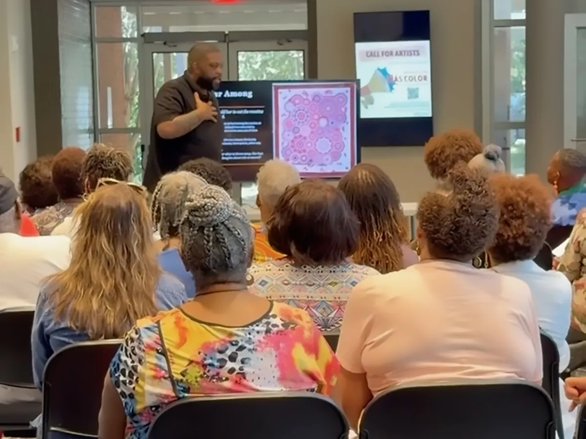 Wesley Hall gesturing toward a projected quilt image while presenting to seated attendees at the Atlanta Quilt Festival