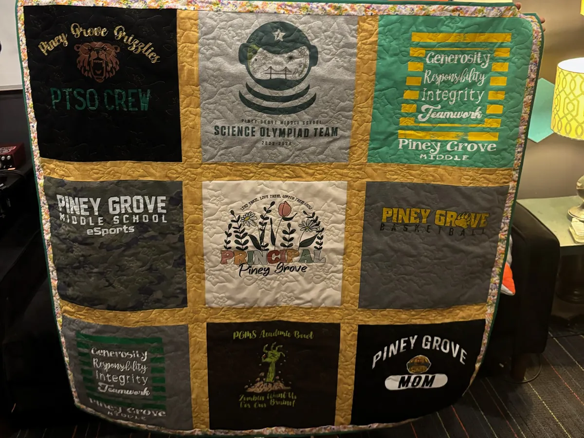 Close-up of a retirement quilt made from nine principal shirts, showing large centered graphics and careful block layout, made by Quilts by Big Wes in Atlanta
