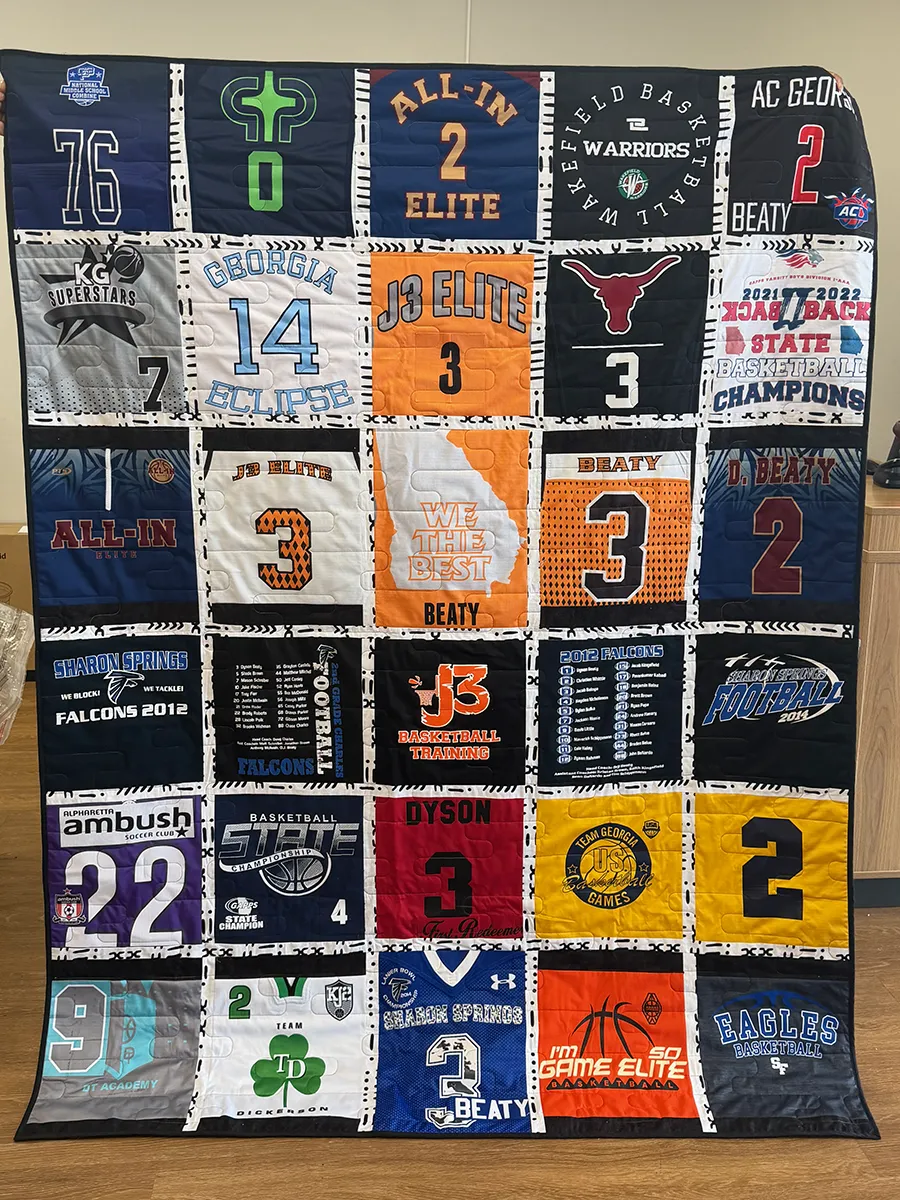 Individual jersey blocks laid out on the quilting table at the Atlanta studio, showing the range of sizes from primary school to high school