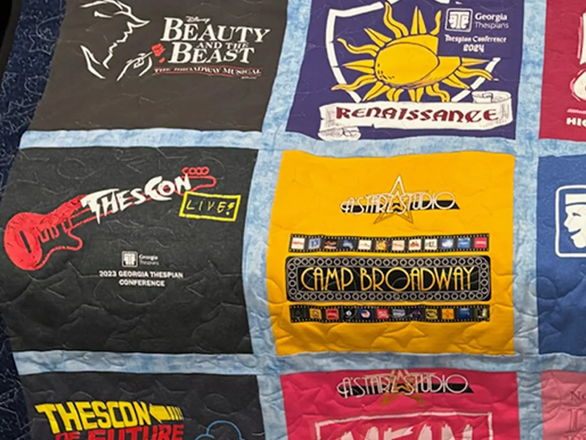 Close-up of a high school theater t-shirt memory quilt with star border fabric and star stitch quilting, resting on a couch in Wesley Hall's Atlanta studio