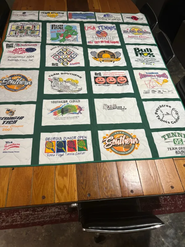 Tennis career t-shirt quilt with dark green sashing, featuring USTA, Georgia Junior Open, Team Atlanta, and Bull Frog tournament shirts, handmade by Quilts by Big Wes