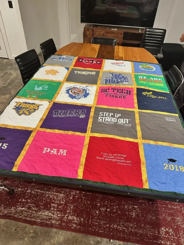 SC Tech Tigers graduation and school spirit t-shirt quilt on a table, featuring Tigers, FBLA, and Georgia PBL shirts with gold sashing, made by Quilts by Big Wes