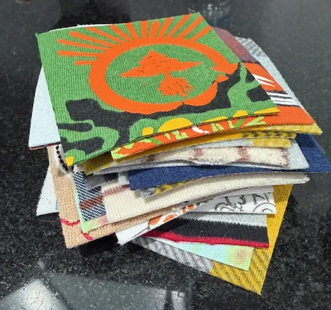 Cut t-shirt quilt blocks laid out flat in the Quilts by Big Wes Atlanta studio, showing a variety of colors and graphic sizes ready for layout